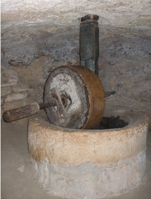 olive_crusher a picture of a large stone wheel on a pedestal that could crush olives in a circular pit